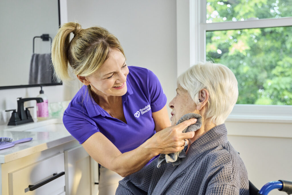Touching Hearts at Home caregiver enjoying tea with a senior client, illustrating brand trust in a Home Care Franchise vs. Independent business model.